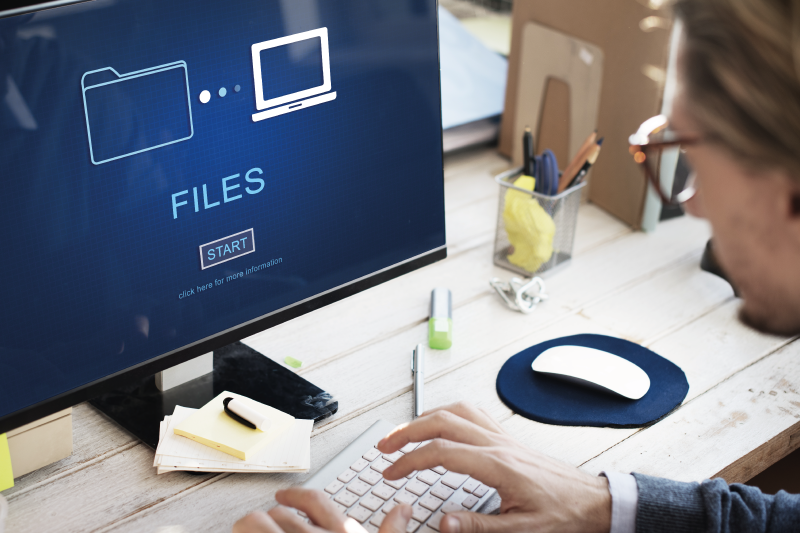 Person with glasses backing up files on screen of computer