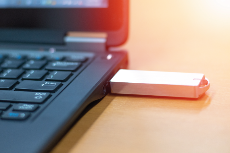 Silver USB flash drive plugged into black laptop