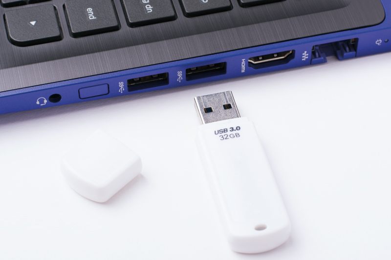 white USB 3.0 32GB flash drive uncapped next to blue laptop ports