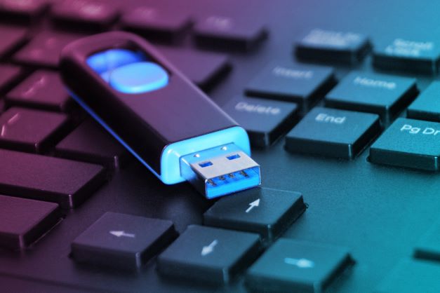 USB flash drive glowing with blue light on top of keyboard