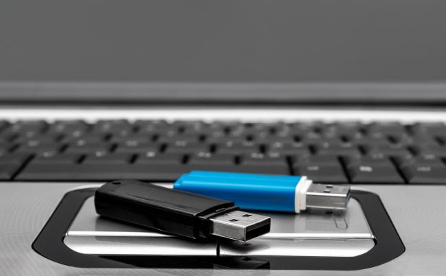 Blue and Black USB flash drives sitting on top of black and silver keyboard
