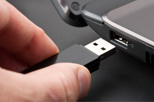hand plugging black usb flash drive into usb port