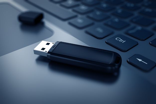 Black USB flash drive sitting atop a keyboard